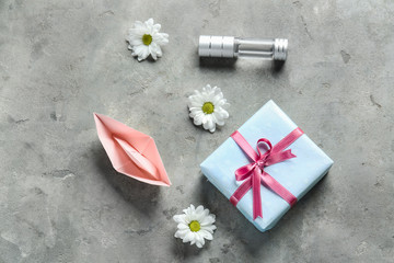Gift box with bottle of perfume, origami boat and flowers on grunge background