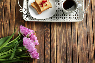 Beautiful tulips with tasty breakfast on wooden table