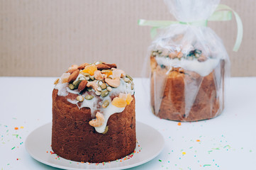 Delicious freshly baked Easter cake with icing, nuts, seeds, candied fruit, multicolored sweet sprinkles, served and packed. Easter, birthday greeting card or web banner concept. Selective focus