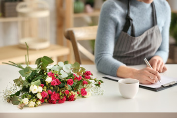 Beautiful female florist working at table in shop