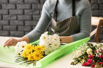 Beautiful female florist working at table in shop