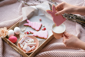 Woman eating tasty Easter cookie with milk