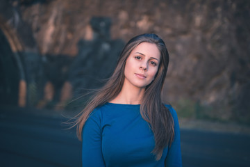 Naklejka premium Girl in a blue long sleeve shirt on a street. Golden hour portrait.