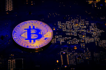 Concept of Bitcoin Mining. Golden Bitcoin on the microchip board close up. Dark background.