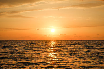 Golden, Fiery sunset on the Black Sea, on the beach. Coast, stones, waves, sun, beautiful sky, clouds. August, Batumi, Georgia. Water, ease, game. plane in the sky, tourism