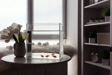 Beautiful aquarium and vase with flowers on table in room