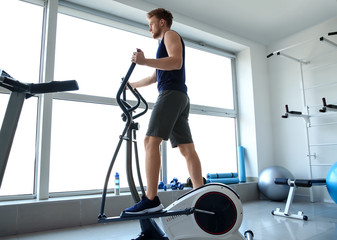 Fototapeta na wymiar Sporty young man training on machine in gym