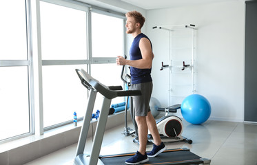 Fototapeta na wymiar Sporty young man training on treadmill in gym