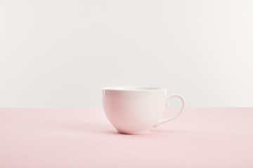 white cup with drink on pink surface isolated on grey