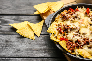 Tasty Mexican dish with nachos on table