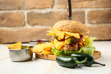 Tasty burger with nachos and guacamole on table
