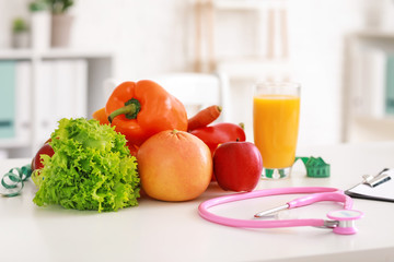 Healthy products and stethoscope on table in nutritionist's office