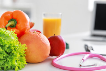 Healthy products and stethoscope on table in nutritionist's office