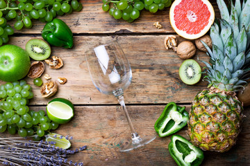 Wine concept. Glass of young white bio wine with green grapes, grapefruit and other fruit on an old wooden table