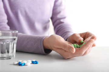 Woman with pills at table, closeup