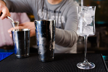 Expert barman is making cocktail at night club, Barman holds a cocktail in his hand. No face. Selective focus