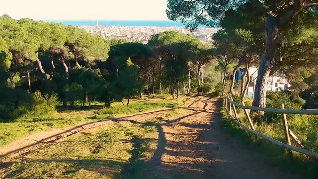 Drone flying backwards and up in the woods revealing barcelona view from sarria uptown