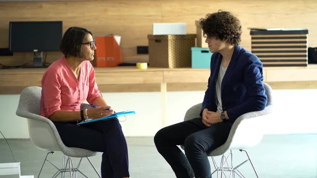 Businesswoman talking with young man during job interview at office