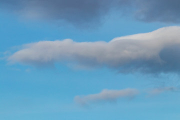 Spring evening sky background with white and grey cumulus clouds on warm sunset