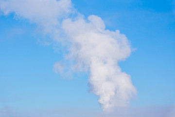 Smoke from one pipe on blue sky background in a cold winter day. City pollution in historical Saint-Petersburg, Russia