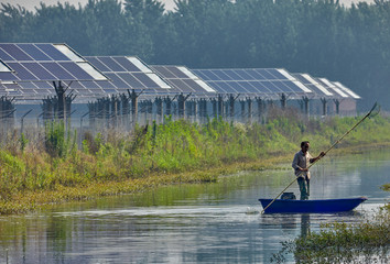 Asian fishermen rowing in the rivers of the solar photovoltaic district