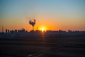 Panoramic view of sunset in the city with silhouette of buildings and industrial factory,pollution city or town concept.