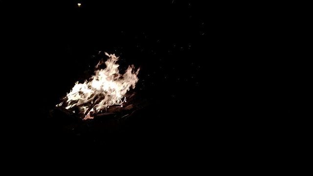 Sparks fly off a burning campfire.