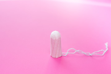 Medical female tampon on a pink background. Hygienic white tampon for women. Cotton swab. Only one tampon on a pink background. copy space