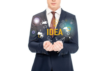 cropped view of businessman in suit with outstretched hands and idea lettering and icons above isolated on white