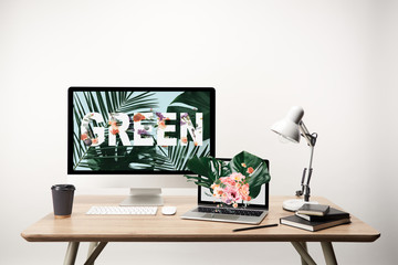 computer with green lettering and monstera leaves illustration on monitor on wooden table