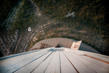 Young woman in a meadow in white t-shirt. Next to her is a white bicycle. View from above. wide-angle photography.