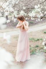 Young beautiful girl walking in blooming magnolias