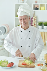 Portrait of elderly male chef cooking at kitchen