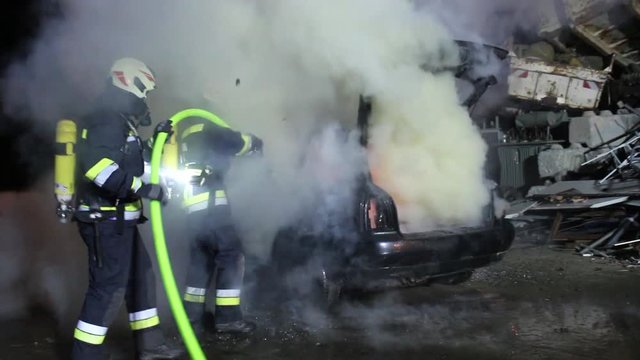 firefighter extinguish a carfire with water huge flames