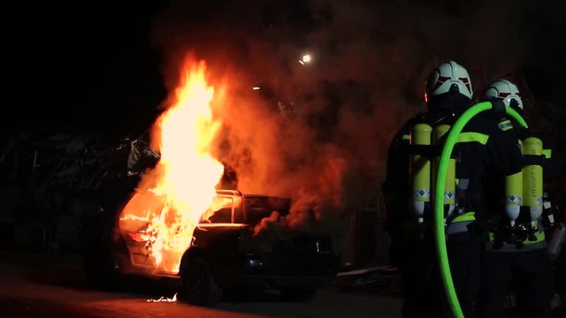 a car is burning fire firefighters extingusih the flames firefighter