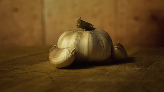 Head of garlic and cloves of garlic on wodden desk. Rotating, turntable shot. Still life