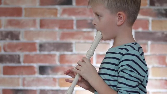 Little boy playing the flute at home