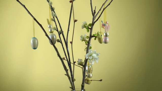 Weidenk&auml;tzchen &Auml;ste und Apfelbaum &Auml;ste in einer Glasvase. Die Apfelbl&uuml;te hat begonnen. Die &Auml;ste werden von einer Frauenhand mit Osterhasen und Ostereiern dekoriert.