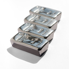 Four cast silver bars isolated on white background. Selective focus.