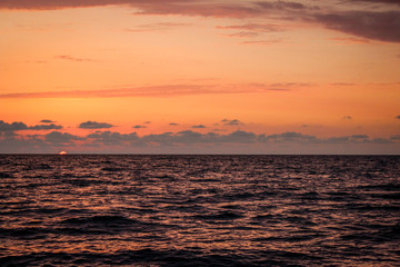 Golden, Fiery sunset on the Black Sea, on the beach. Coast, stones, waves, sun, beautiful sky, clouds. August, Batumi, Georgia. Water, lightness, play. Pink, lilac, crimson