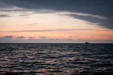 Golden, Fiery sunset on the Black Sea, on the beach. Coast, stones, waves, sun, beautiful sky, clouds. August, Batumi, Georgia. Boat, ship. Water, lightness, play. Pink, lilac, crimson