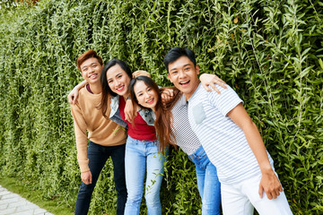 Happy friend posing near hedge