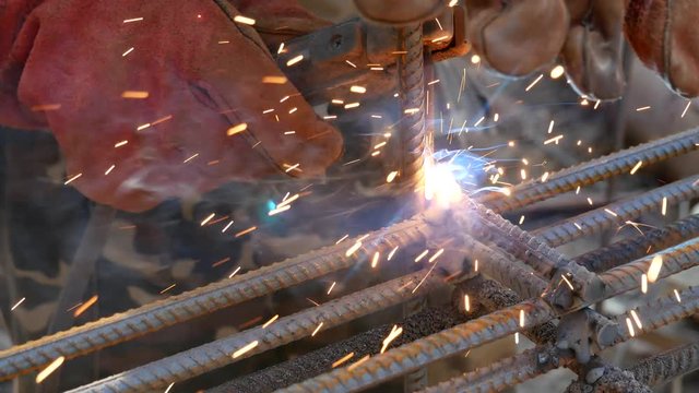 Electrode welds metal. Hand welder in mittens with electrode holder. Electrode weld reinforcing bars. Sparks crumble to the side. Welding and cutting of iron rods. Kiev. Ukraine. October 19, 2017