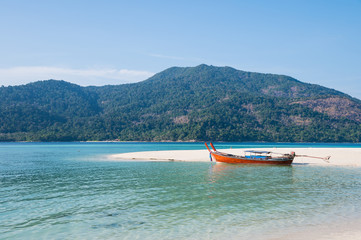 White sand beach with wooden long-tail boat in tropical sea