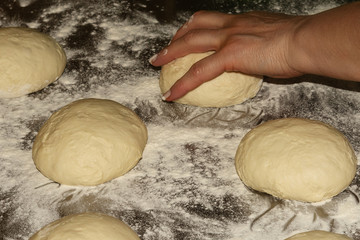 Traditional Caucasian cuisine. Elderly woman cooks dough for the Ossetian pies. Preparing dough stretching ball kneading. Close up. Selective focus.