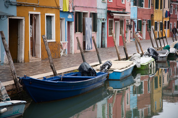 Fototapeta na wymiar Features old multicolored houses. Water channel with boats used for transporting goods and people. Geometry of windows and doors in the colorful houses of the island of Burano, Venice, Italy