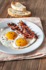 Fried eggs and bacon on the white plate