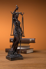 selective focus of bronze statuette with scales of justice and volumes of brown books on wooden table