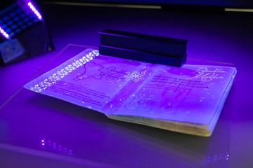 Process of the Moldovan passport checking, close-up. The study of protective elements of the document in ultraviolet light. High security printing for passport. Passport protection against fraud