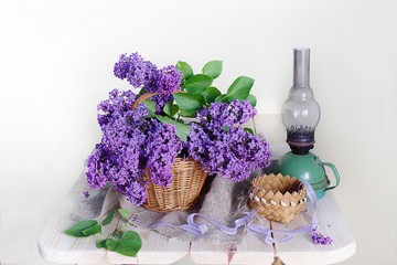 Still life with lilac flowers and vintage kerosene lamp on white background .